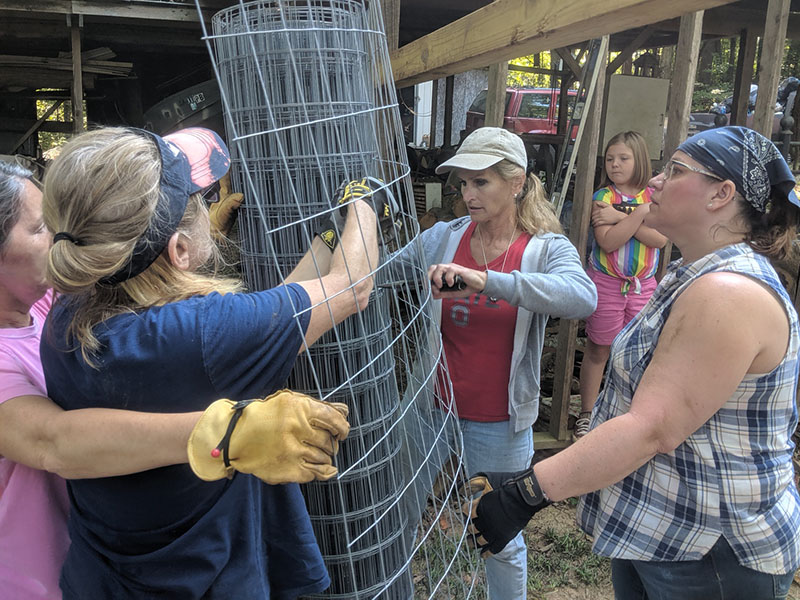 Freedom for Fido volunteers Dana Worm, Vicki Middleton and Missy Playford unwrap fencing on a recent fence build enabling the family’s dogs to run around the yard instead of being chained up.
