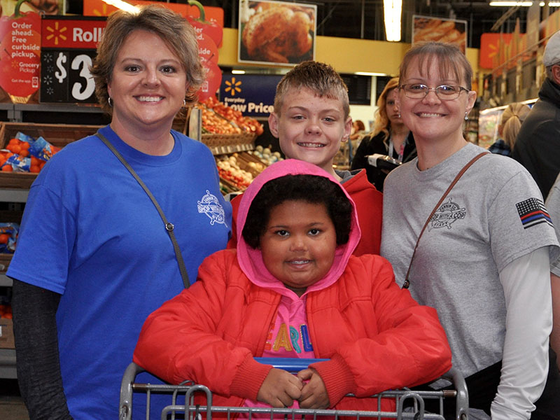 Memori Sorensen, front, pushes the buggy while searching for some presents with Shop with a Cop Board Member Dawn Cochran, left, Volunteer Steven Dickey and Board Member Sarah Dickey.