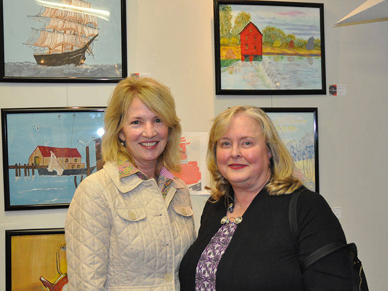 North Georgia Autism Foundation representative Cathy Ritchie and Jan Stahl, the mom of one of the artists who is displayed, chat as they view the art hanging on the walls of the Foundation’s new art gallery micro-buisness.