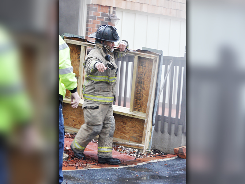 Fannin County firefighter Jason Turner removes part of a covering in order to access the crawl space under the house at 511 Scenic Drive.