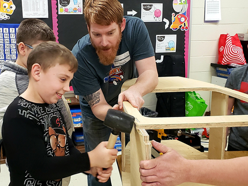 Mike Sullivan, right, helped Aryan Pack, left, and Hayden Bryan put together a soap box derby car at East Fannin Elementary School last week.
