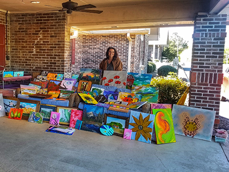 Jennifer Danner stands behind a plethora of paintings created by herself and other members of the community for the residents at the Life Care Center of Copper Basin. The paintings were delivered Thursday, April 2.