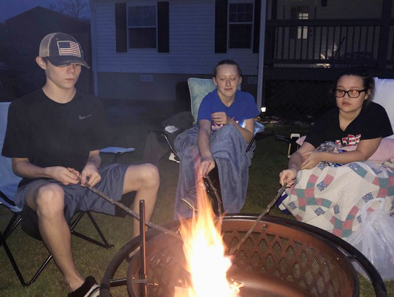 Fannin County Middle School student Jordan Buchanan, left, and Fannin County High School students Jasmine Jackson, middle, and Madison Buchanan enjoy making s’mores and staying warm by a fire pit while they are out of school.