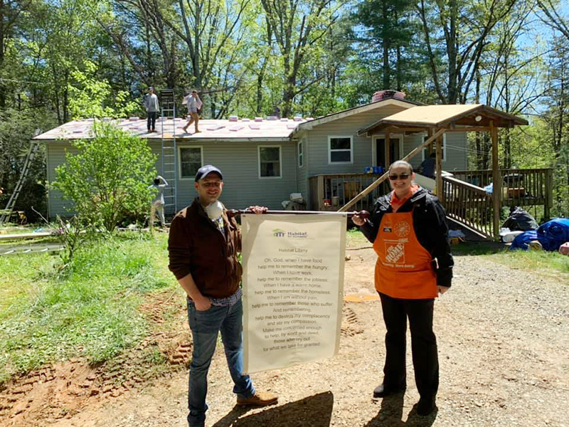 Habitat for Humanity of Fannin and Gilmer Counties Executive Director Chris Hall holds their mission statement, alongside Holly Chandler of Home Depot, during a recent roofing project.