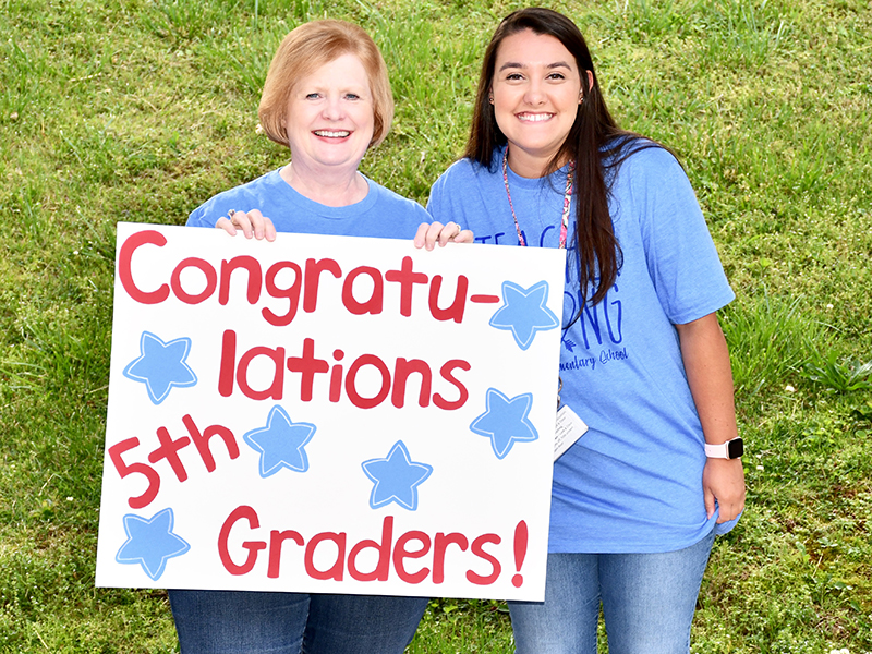 Blue Ridge Elementary School Art/Music/Drama Teacher Nancy Watkins, left, and Pre-K Teacher Sarah Adams congratulate fifth graders during the school’s Fifth Grade Drive-Thru Parade Tuesday, May 19.