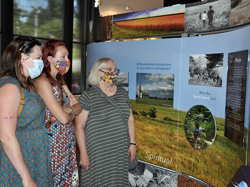 Crossroads: Change in Rural America Co-Curator Dr. Ann McCleary, right, explains the exhibit to, left, Sarah Wright and Emma Bussard at the exhibition’s grand opening Saturday, June 20.