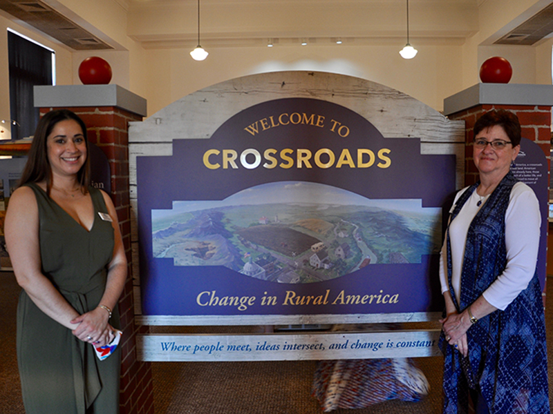Blue Ridge Mountains Arts Association Executive Director Nichole Potzauf, left, and Assistant Director Caroline Mann stand before the long-awaited “Crossroads: Change in Rural America” exhibition Saturday, June 20. The exhibition is in partnership with the Smithsonian Institute’s Museum on Main Street, Georgia Humanities, the University of West Georgia and Georgia EMC. It will continue at The Art Center through July 17.