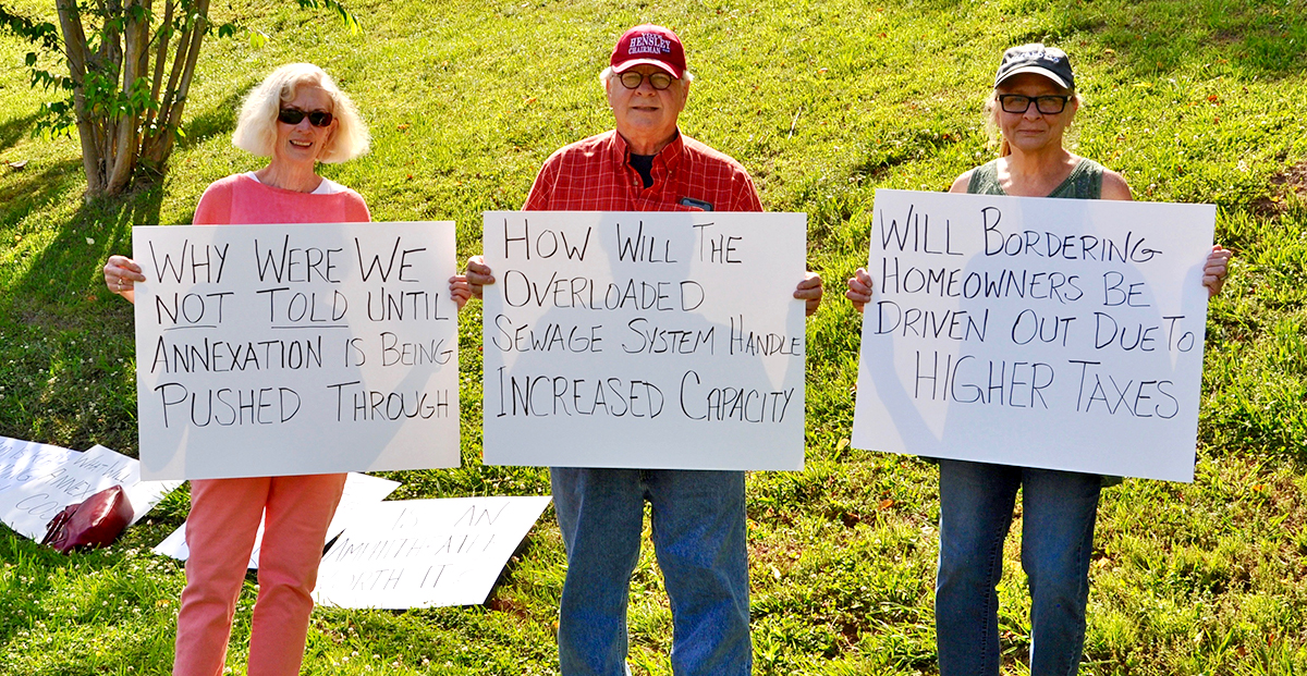 Libby Young, Kirk Williams and Dana Worm waited outside Blue Ridge City Hall holding signs with questions regarding the proposed annexations of highways 5 and 515.