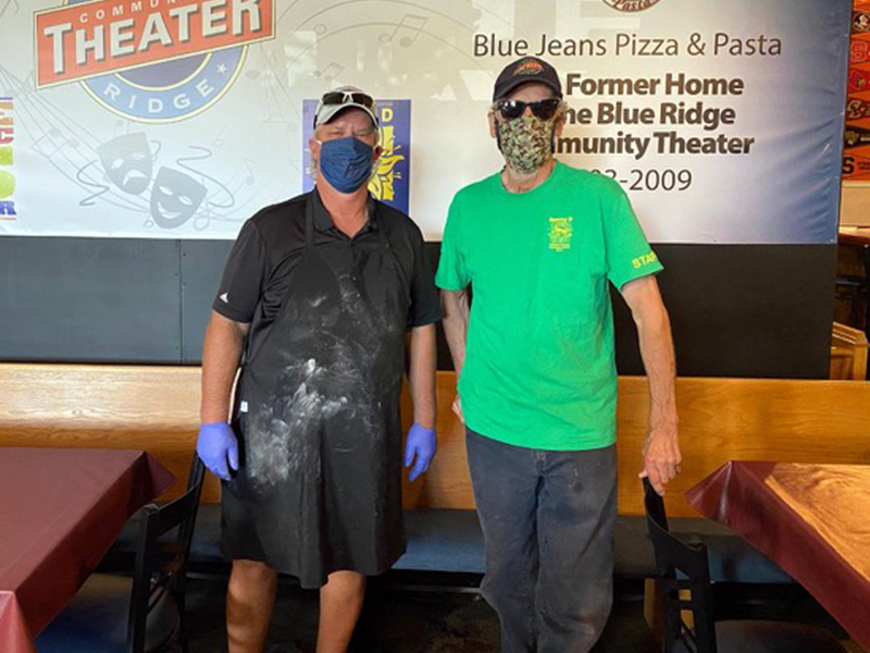 Blue Jeans Pizza and Pasta Factory owner Ken Brenneman, left, and Blue Ridge Community Theater (BRCT) Emeritus Joe Webb stand before a wall built by the theater’s set builders for the restaurant.