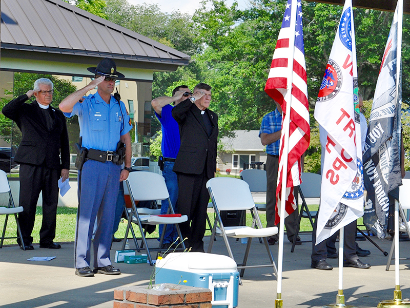 Local clergy members, law enforcement officers, first responders and community members gathered in Blue Ridge’s downtown park to pray for the nation Saturday, July 18. Public servants are shown saluting the flags during the National Anthem.