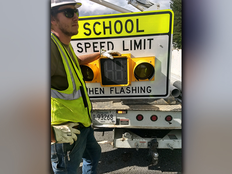 A worker from Nabco Electric is shown with one of the flashing school zone lights installed on Highway 68 in front of the entrance to Copper Basin schools.