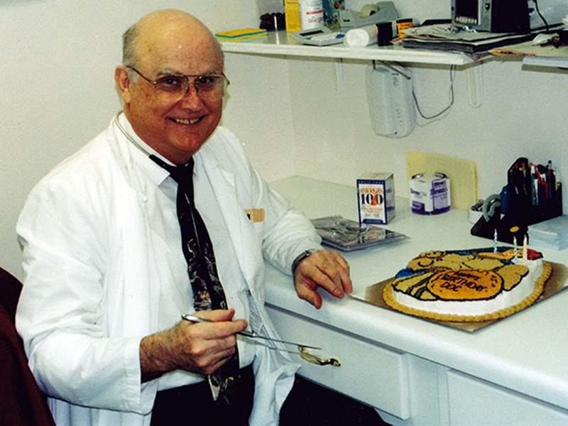 The late Dr. James Haymore III is shown in his office smiling before cutting his birthday cake from years past.