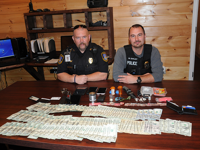 Detective Cory Collogan, left, and Chief Mike Earley of the McCaysville Police Department are shown with the cash, drugs and other assorted items seized Saturday night in connection with the arrest of Brian Joseph Martell.