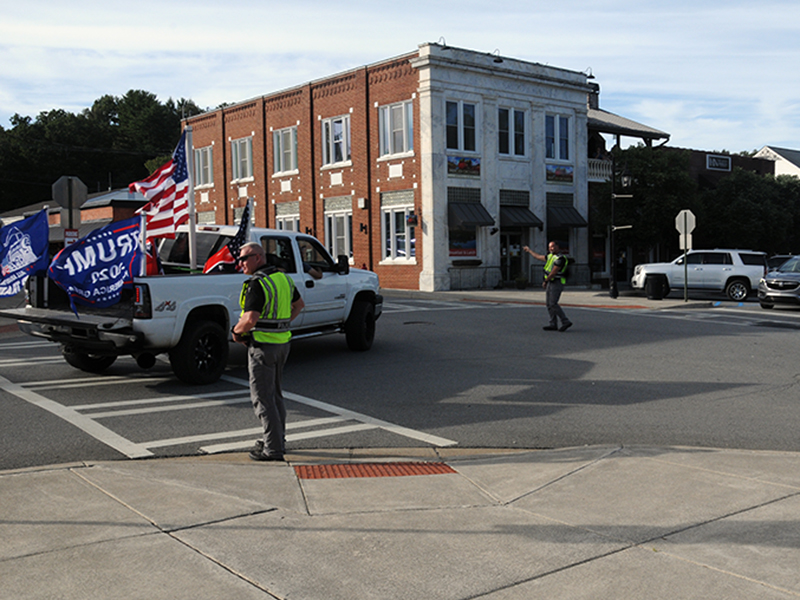 Blue Ridge police officers, from left, Patrolman Thomas Davis, Captain Robbie Stuart and Chief Johnny Scearce, are shown directing one of the approximate 50 to 75 vehicles flying a variety of flags through Blue Ridge Saturday evening. They are at the intersection of West Main and Depot streets.
