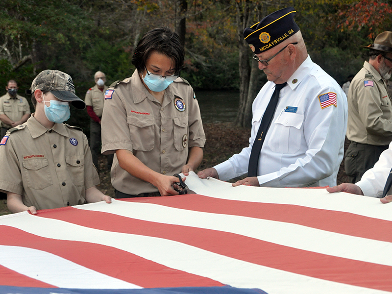 Boy Scout Jefferson Lewis cuts the stripes of an American flag while North Georgia Honor Guard member Richard Crosley holds the flag during a Flag Retirement Ceremony Tuesday, October 20. The ceremony was conducted at Ron Henry Horseshoe Bend Park by honor guard members and Epworth Scout Troop 32.