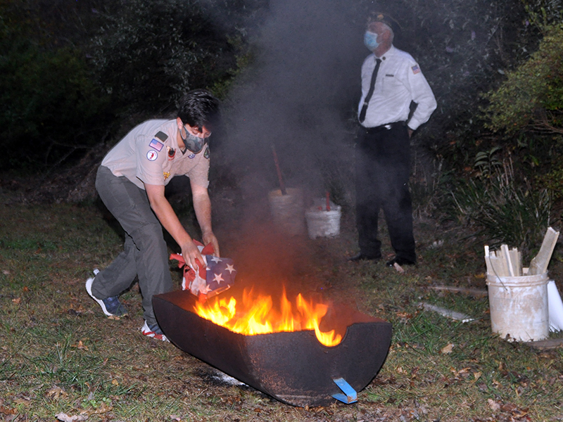 Boyscout Chase Roll gently lays a retired flag into the fire to be burned at a Flag Retirement Ceremony at Horseshoe Bend Park Tuesday, October 20.