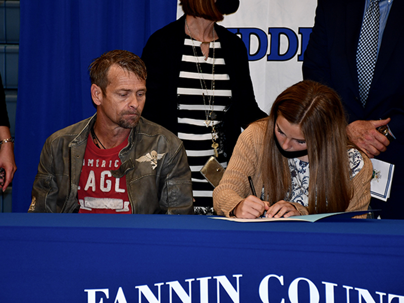 Fannin County Middle School student Jacee Fain signs her Realizing Educational Achievement Can Happen (REACH) contract as her father, Nathan Fain, looks on during the REACH Signing Ceremony Wednesday, October 21.
