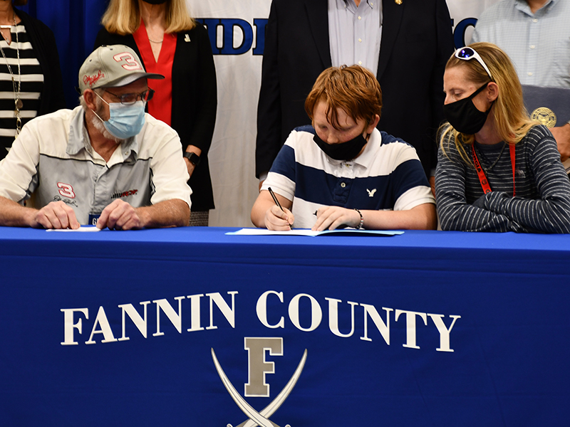 Fannin County Middle School student Rilee Flowers signs his Realizing Educational Achievement Can Happen (REACH) contract as his parents, James and Melissa Flowers, wait to sign their own agreements during the REACH Signing Ceremony Wednesday, October 21.