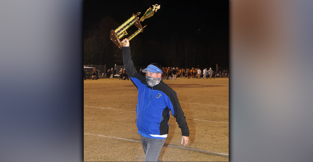 Fannin Rebel football Head Coach Chad Cheatham smiles as he hoists the Region 7AA Championship trophy after Fannin’s 55-7 win over Dade County Friday, November 20.