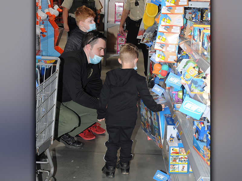Fannin County Detention Sergeant Tyler Limburg had his hands full helping two youngsters pick out gifts during Shop With A Cop Saturday.