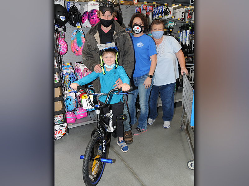 Shop With A Cop counts on many volunteers to help make the annual program a success, such as Fannin County Chief Tax Appraiser Dawn Cochran. She is shown, third from left, with Levi Lacy who is all smiles as he shows off his brand new bicycle. Jason Long and Merilee Bennett were also there when Lacy made his choice during the event Saturday at the Blue Ridge Walmart.