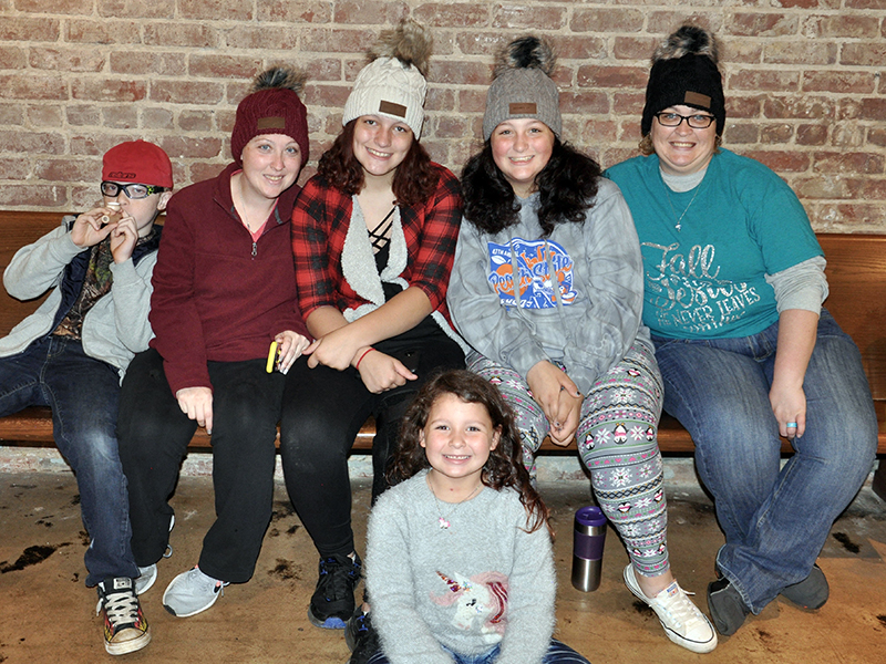 Braden Hamilton, KB Hamilton, Valere Cash, Bristol Cash, Abby Cash and Kendra Cash, from left, found a spot inside the Riverwalk Shops to take a load off before the Light Up McCaysville tree lighting Friday, November 27.