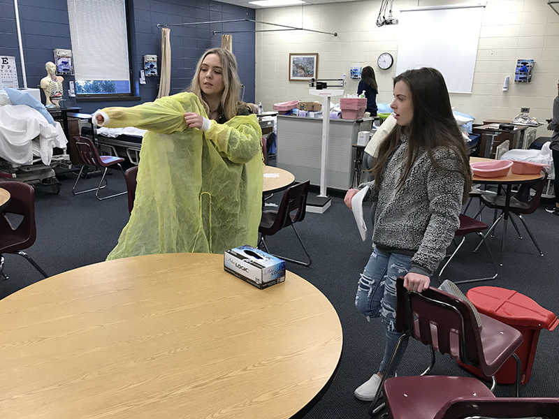 Fannin County High School student Ella Richardson, left, is shown being evaluated by her fellow student, Karly Waters, on the proper application and removal of personal protective equipment in Healthcare Science teacher Anne Gibbs’ Patient Care Fundamentals course.
