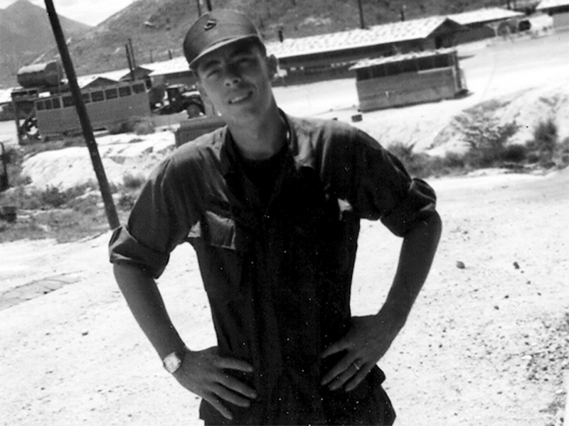 Army veteran Paul Hunter is seen at a fuel dump with the mountains of Quinn Yan, Vietnam, in the background.