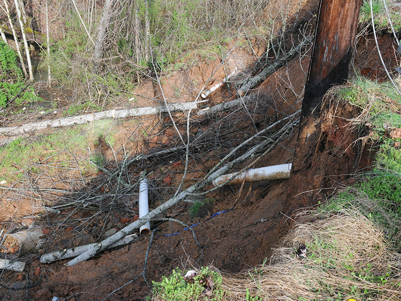 A City of Blue Ridge water line lies broken below a power pole, both affected by a washout early Friday morning off Bullen Gap Road.