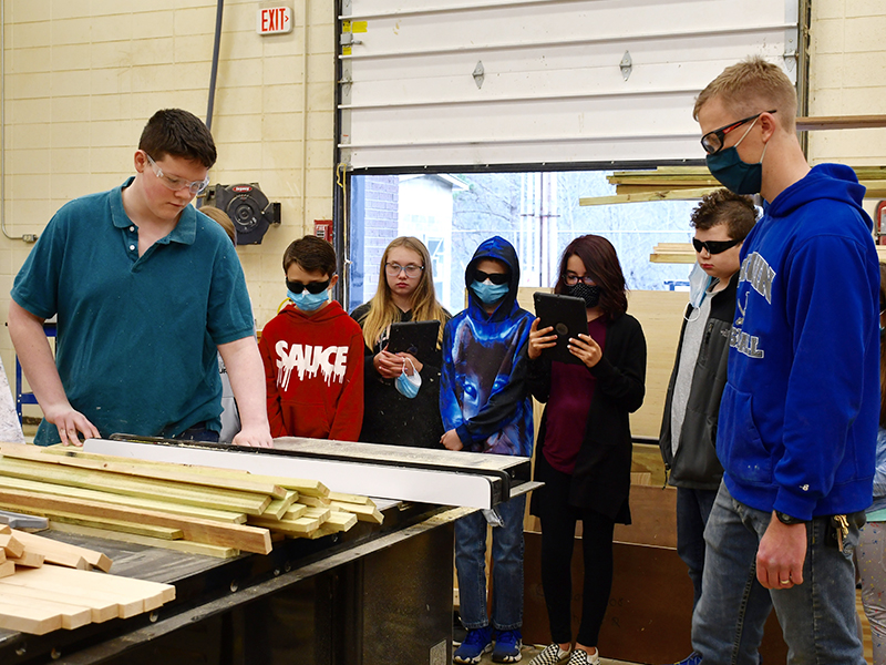 Fannin County High School construction student Trenton Yohn demonstrates the use of a table saw for East Fannin Elementary School students as construction teacher Daniel Stewart watches on. East Fannin students shown are, from left, Brady Cole, Venice Oliver, Rylee McCalley, Izzy Torres and Carter Campbell.