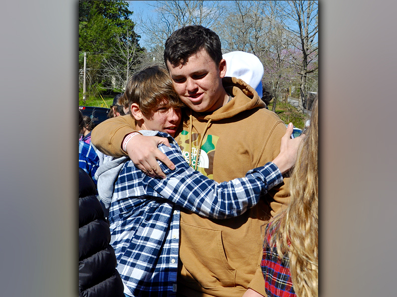Braden Taylor, left, and Case Holloway embrace one another after releasing balloons for friend Shane Adrian “Dewey” Derreberry Thursday, April 1.