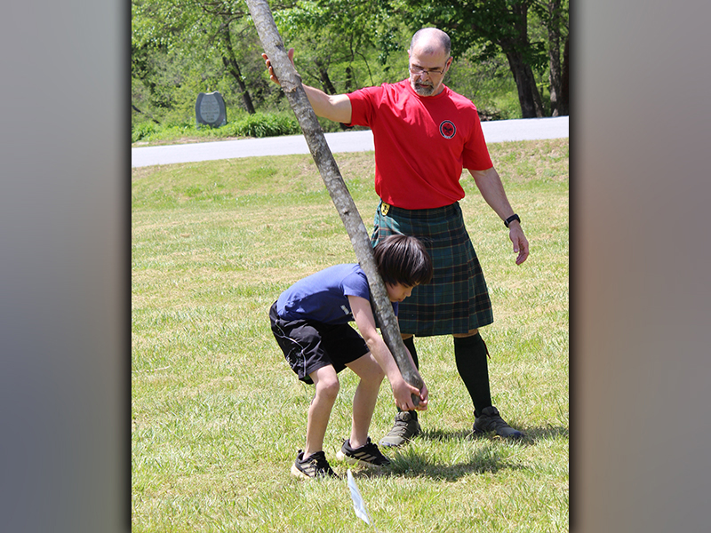 Boy Scout James Grubb learns the caper toss with the help of Tom Lawrence at Troop 32's Highland Games Saturday, May 1.