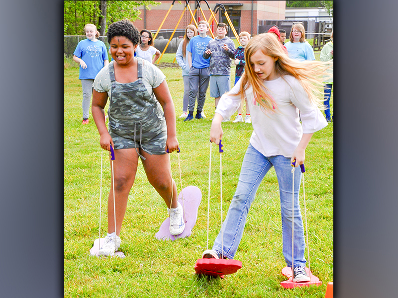 Emma Chambers, left, and Josalyn Deal race each other while sporting very large feet during West Fannin Elementary School’s field day.