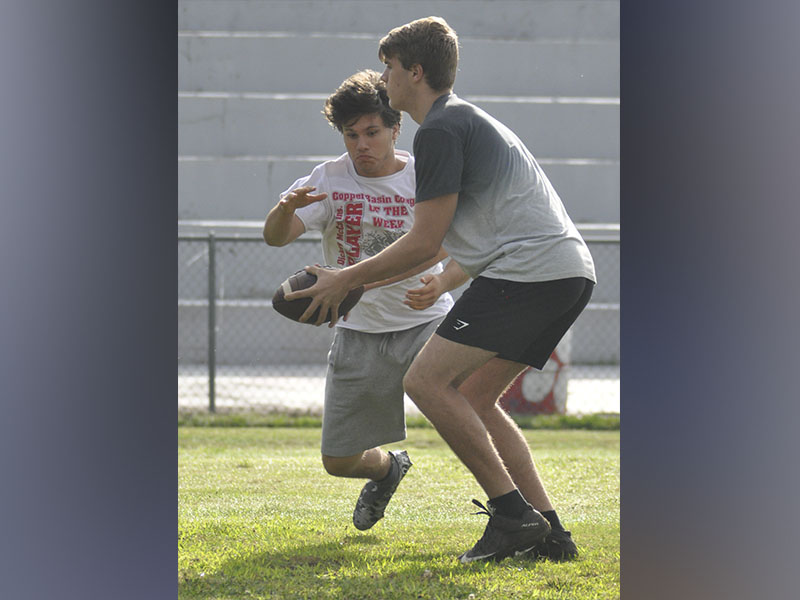 Quarterback Joe Boggs, right, hands the ball off to runningback Sebastian Balilies during the Cougars’ football practice Thursday, June 10.