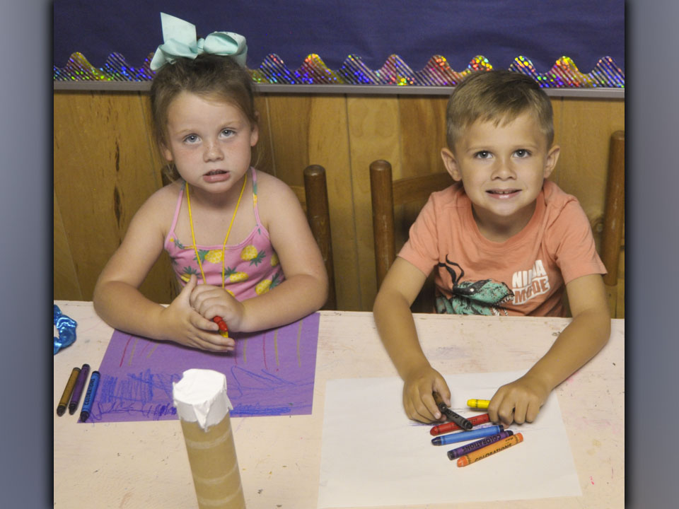 Kreidynce Cook, left, and Brady Reeves take a break from coloring to smile for a photo during McCaysville Gospel Tabernacle’s Vacation Bible School Tuesday, July 13.