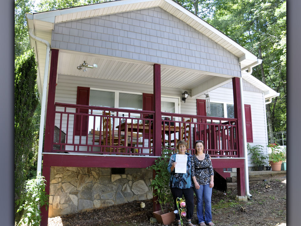 Gloria Ensley stands, deed to her home in hand, with her daughter, Ericia Almond.