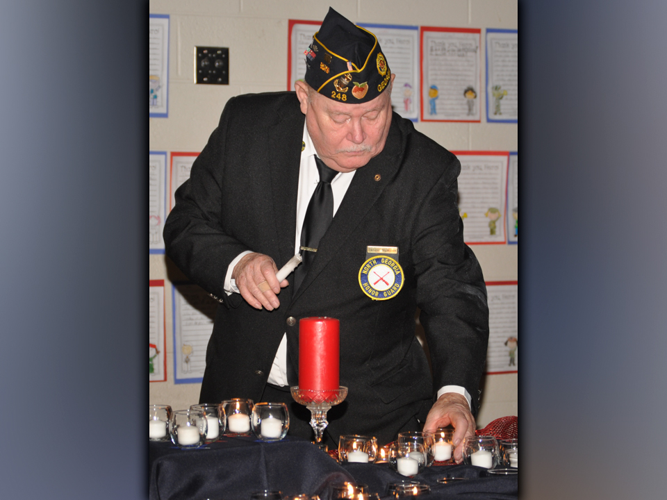 In this photo from 2018, retired U.S. Coast Guard veteran Gerald McMillen lights candles of remembrance during a Veterans Day ceremony at West Fannin Elementary School.