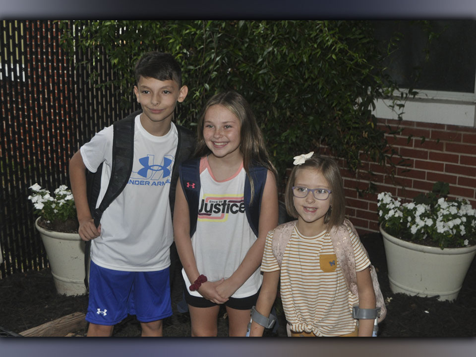 Levi Thomas, left, Jayden Miller, middle, and Allie Thomas put on big grins as they enter West Fannin Elementary School for the first day of classes Friday, July 30.