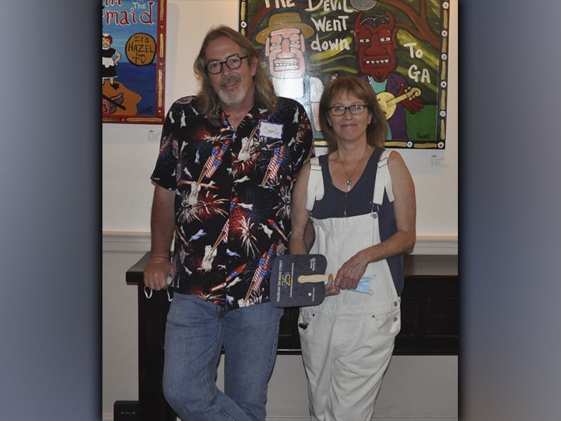 The Blue Ridge Mountains Arts Association held their opening reception for the Contemporary Southern Folk Art exhibit Saturday, September 4. Standing in front of some of his artwork during the reception is artist Sam Granger and Lorri Penn. The exhibit will be open until October 10. 