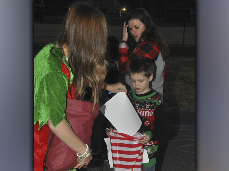 Santa’s helper Cassidy Payne give Koen Williams some gifts while he makes his way to meet Santa Claus during the Winter Wonderland event at the Fannin County Recreation Center Friday, December 3.