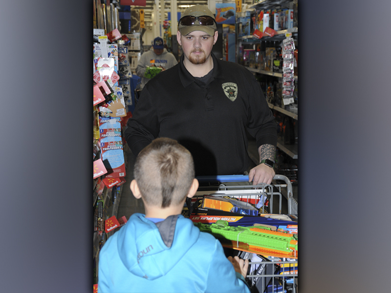 Sergeant Evan Asbury helps a child pick out Christmas toys during Shop With a Cop.