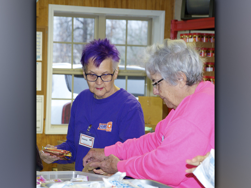 Snack in a Backpack volunteers Joanne Campbell and Anne Brayley help to pack bags of meals to be distributed to children in local schools.