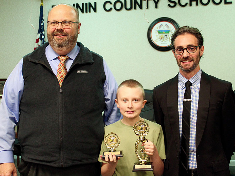 Fannin County Middle School (FCMS) sixth-grader Dylan Hart, middle, proudly holds his trophies after winning the Fannin County School System Spelling Bee, Tuesday, January 25. Shown with him are, FCMS Principal Mark Young, left, and Fannin County School System Director of CTAE/STEM and Spelling Bee caller Lucas Roof, right.