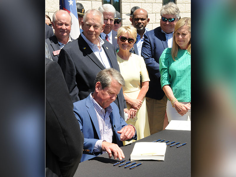 Georgia Governor Brian Kemp, seated, signed the state’s 2023 budget during a special ceremony Thursday, May 12, on the University of North Georgia Blue Ridge campus. Behind Kemp are District 7 Representative and Speaker of the House David Ralston and his wife, Sheree Ralston, Fannin County economic development director. 