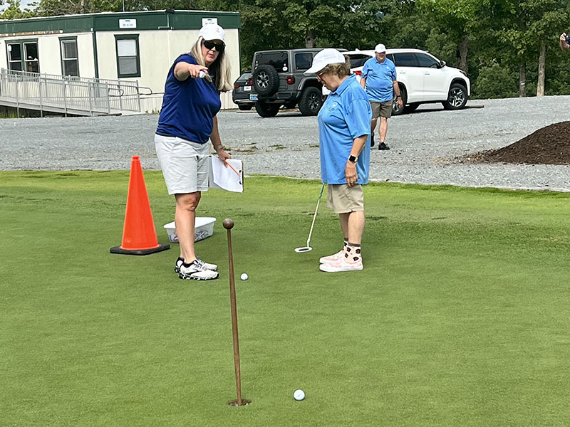 Carrie Minear, left, points athlete Kari Castlen to the hole at the Special Olympics golf event Tuesday, July 19 at Old Toccoa Farm. 