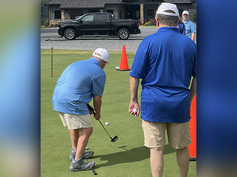 Jay Jenkins, left, takes a putt towards the hole with the guidance of Tom Neuman, right, at the Special Olympics golf event Tuesday, July 19 at Old Toccoa Farms.