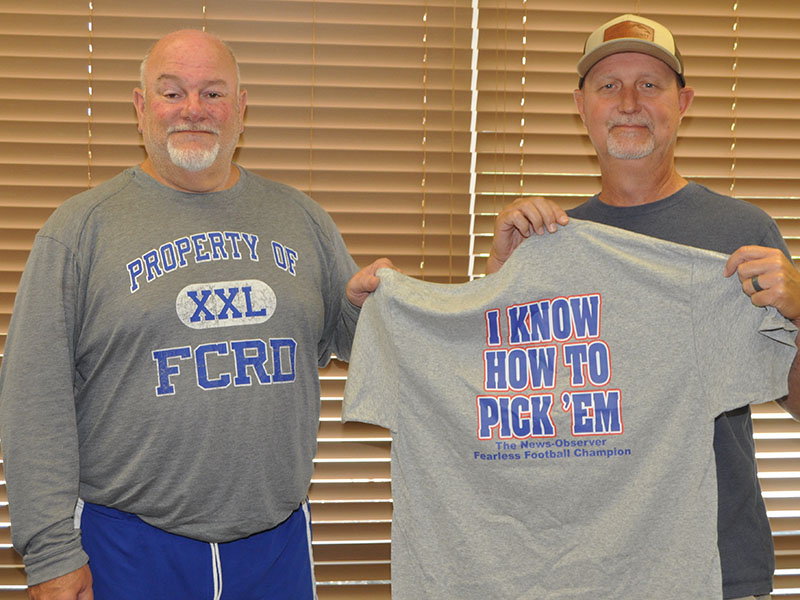 John Spargo, left, awards last year’s Fearless Football Forecaster champion Eddie O’Neal, right, with the championship t-shirt. 