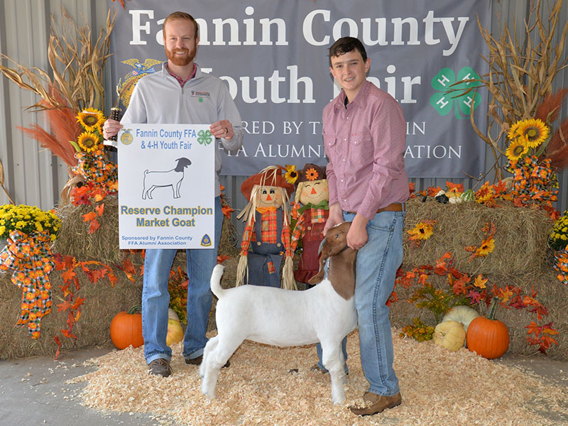 Jacob Williams, a Fannin County High School FFA member, holds onto his prize goat as liverstock judge Dylan Davis displays his award.