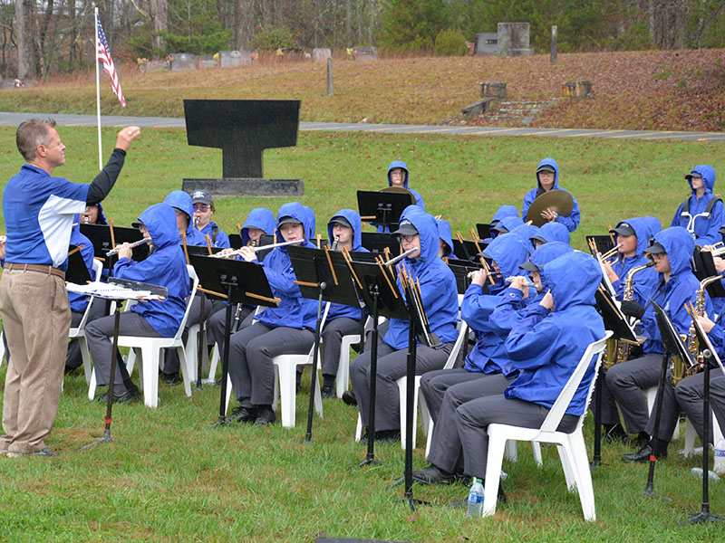 The Fannin County High School band, under the direction of Scott Barnstead, left, braved the Saturday rain to perform patriotic music during ceremonies in the Fannin County Veterans Memorial Park.