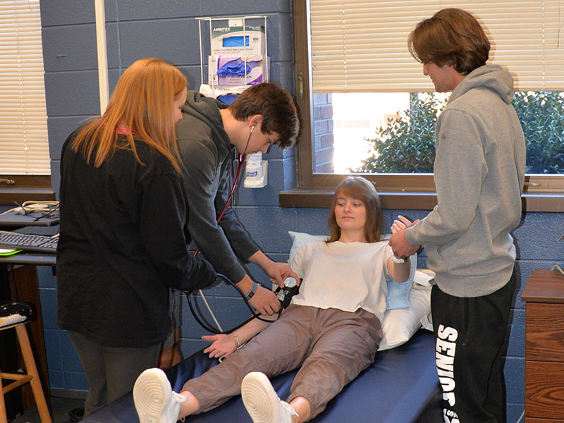 Taking a patient’s blood pressure and pulse are among the basic health care skills Certified Nursing Assistant (CNA) students learn at Fannin County High School. Here, using Clare Payne as the patient, Ivy Hyde, Hayden Danner and Micheal Treon practice the skills.